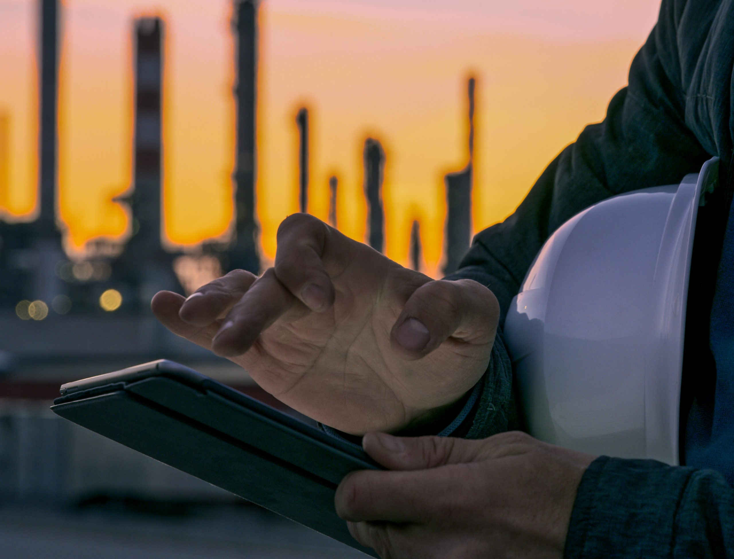 worker using tablet near refinery