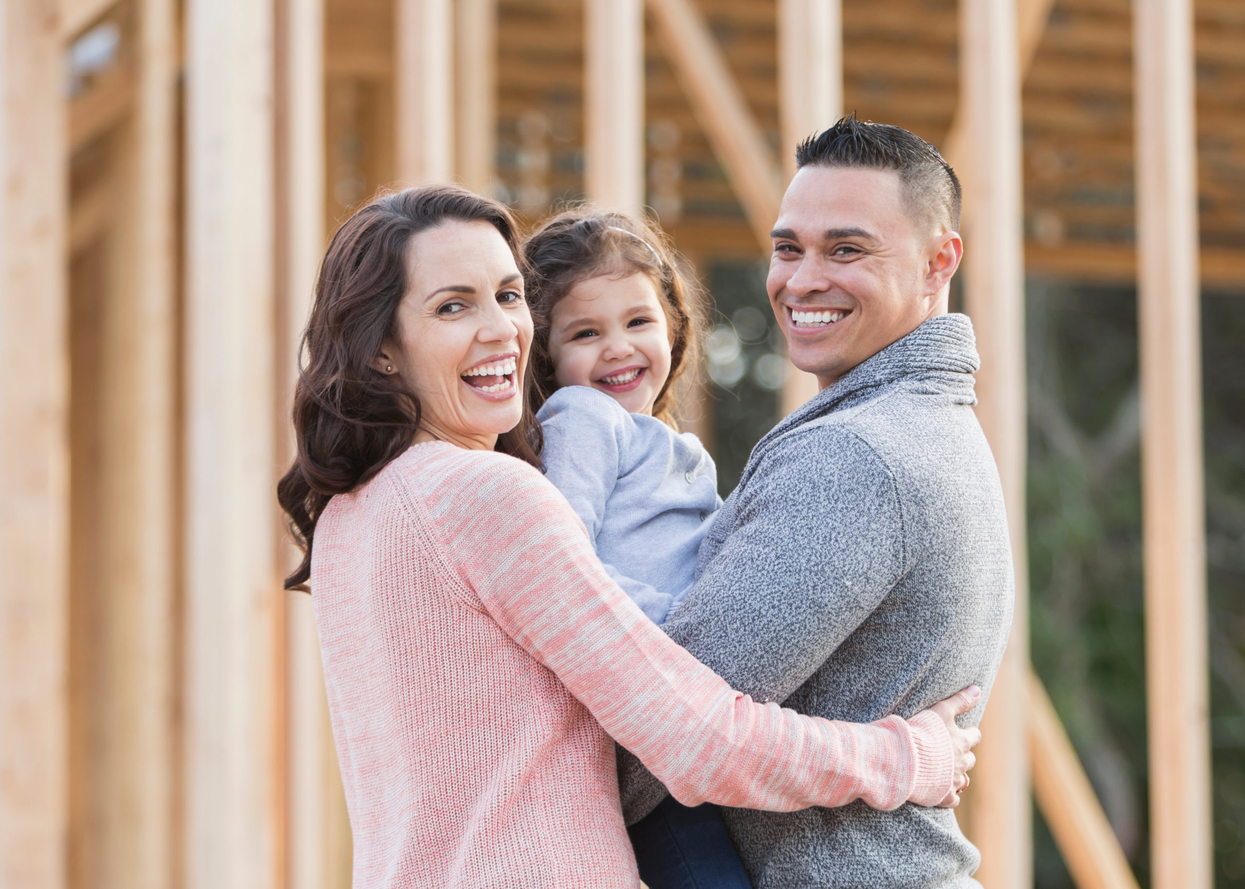 smiling family in front of home construction