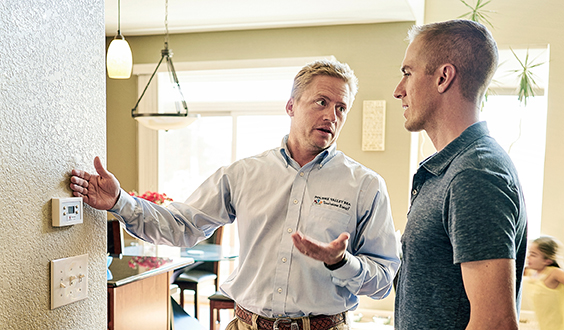 Energy consultant discussing thermostat with homeowner