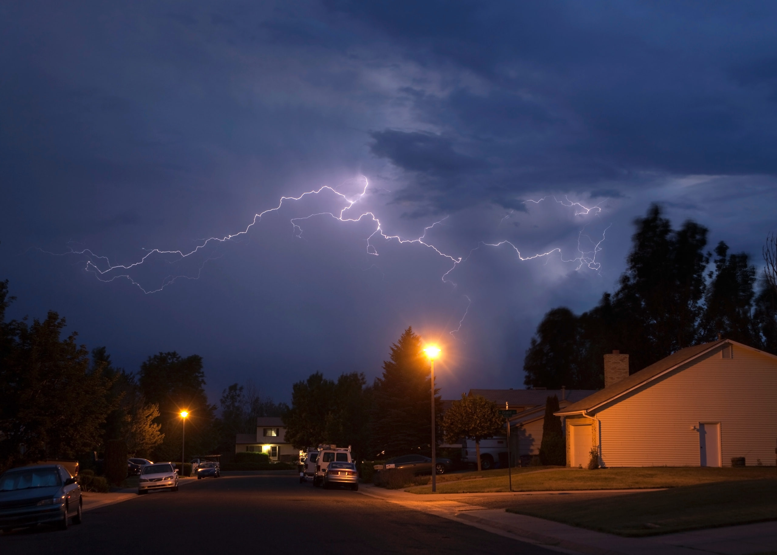 lighting strikes in clouds above neighborhood