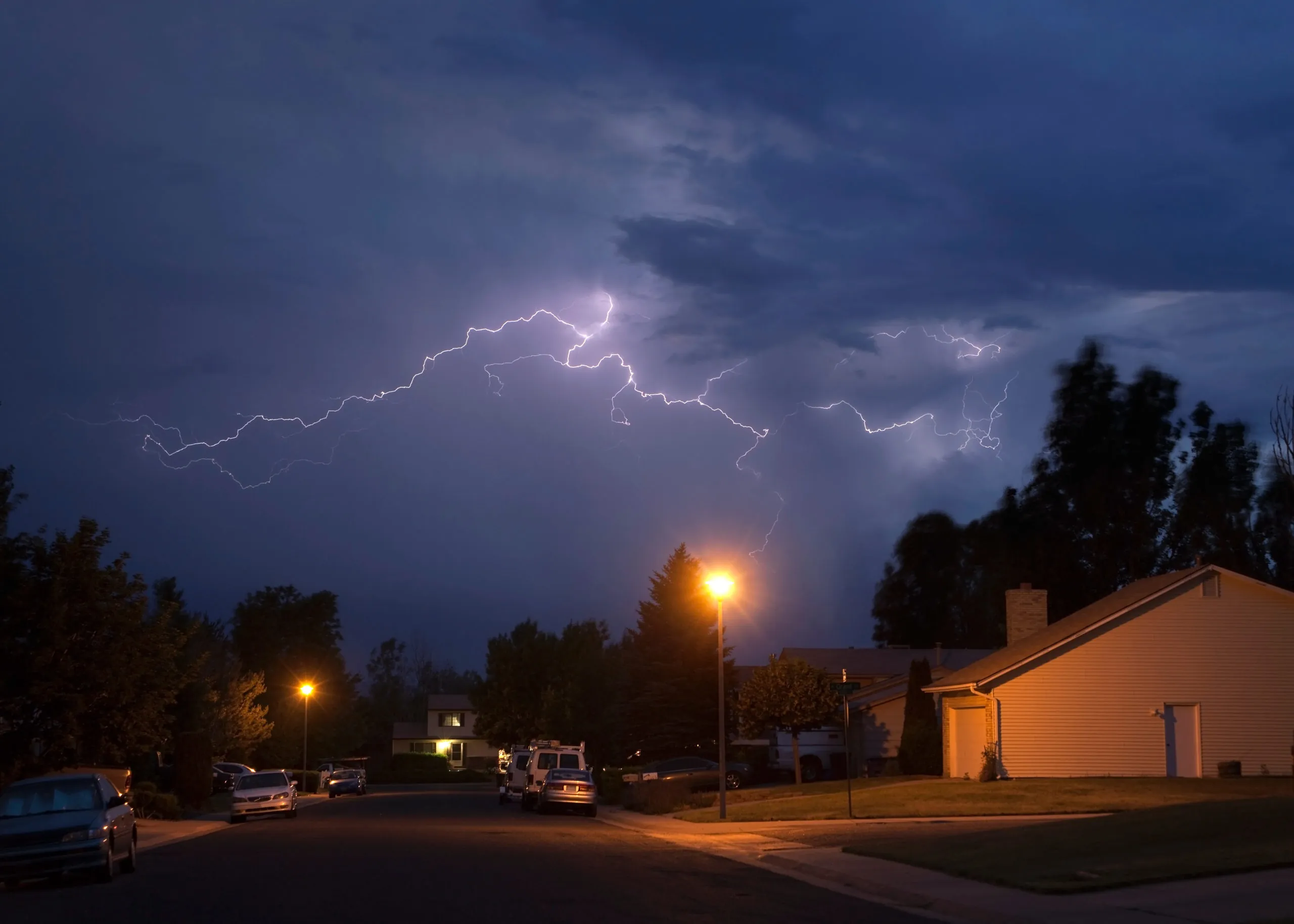 lighting strikes in clouds above neighborhood