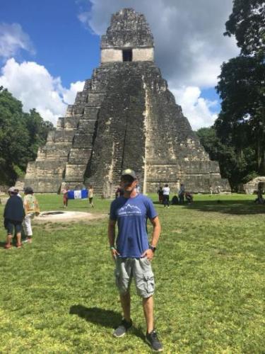 Energy Trails lineman poses in front of an ancient city ruin in Tikal, Peten.