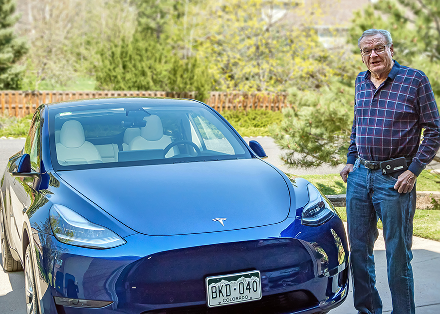 man smiling next to tesla electric car