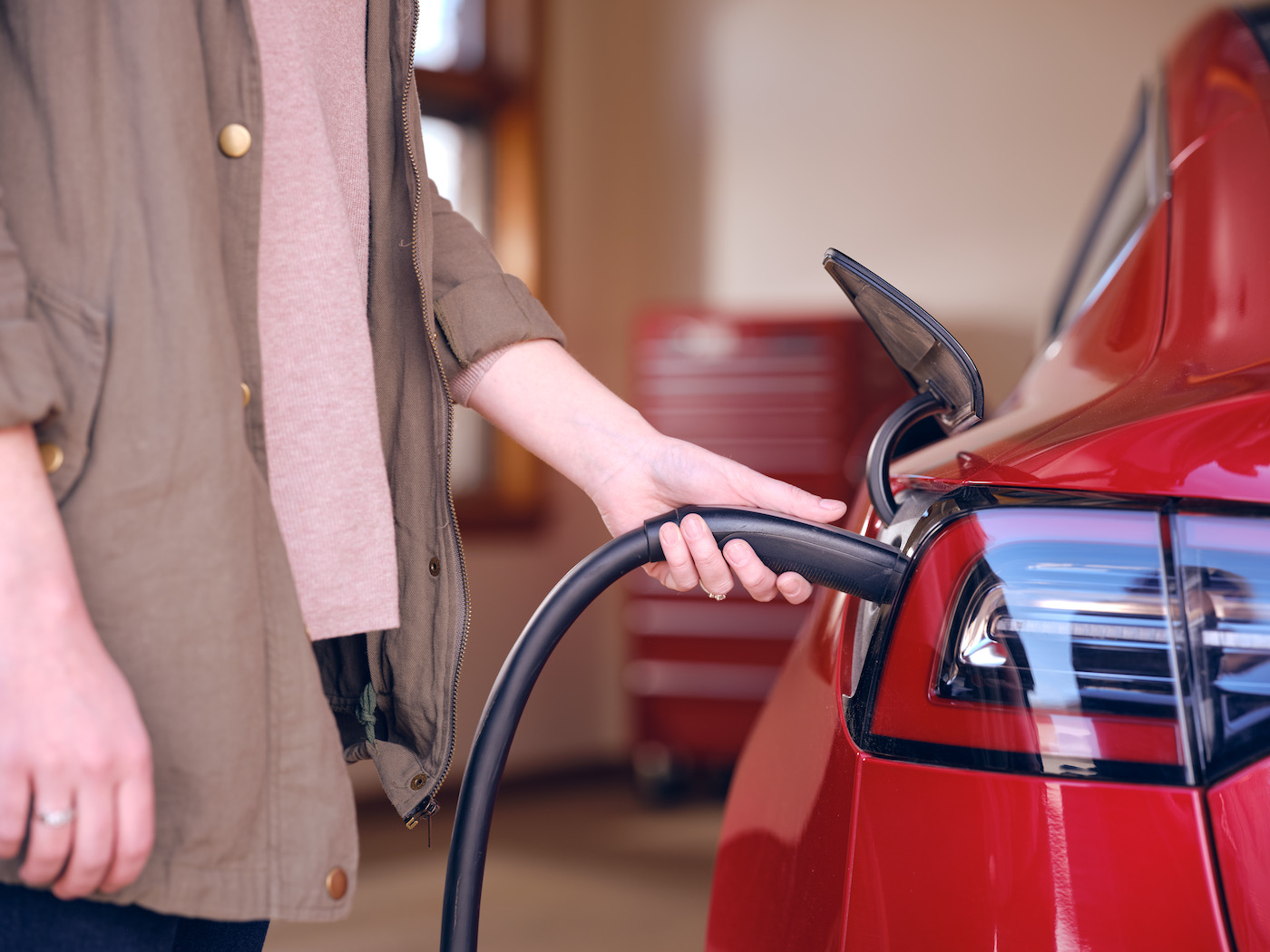 person putting charger into electric vehicle