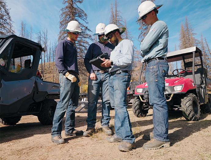 Group of lineman standing together discussing a work project.