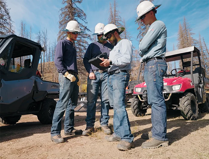 Group of lineman standing together discussing a work project.