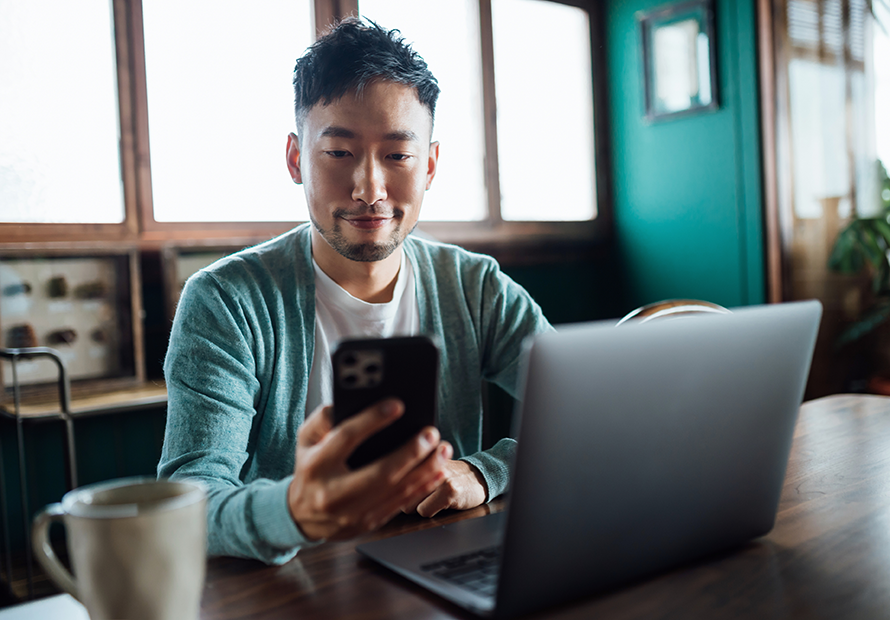 Man checking his phone and laptop.