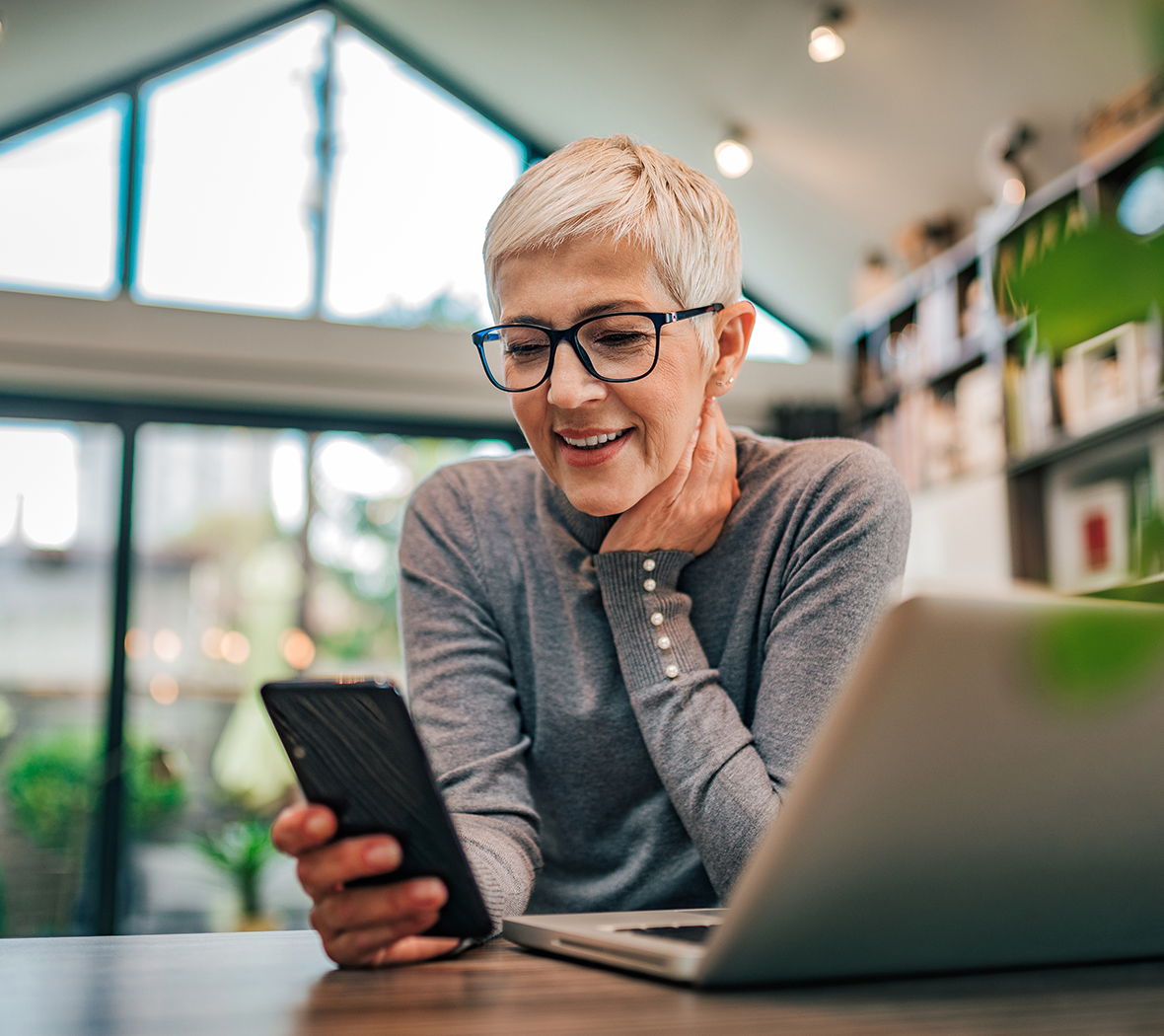 Woman checking phone and computer