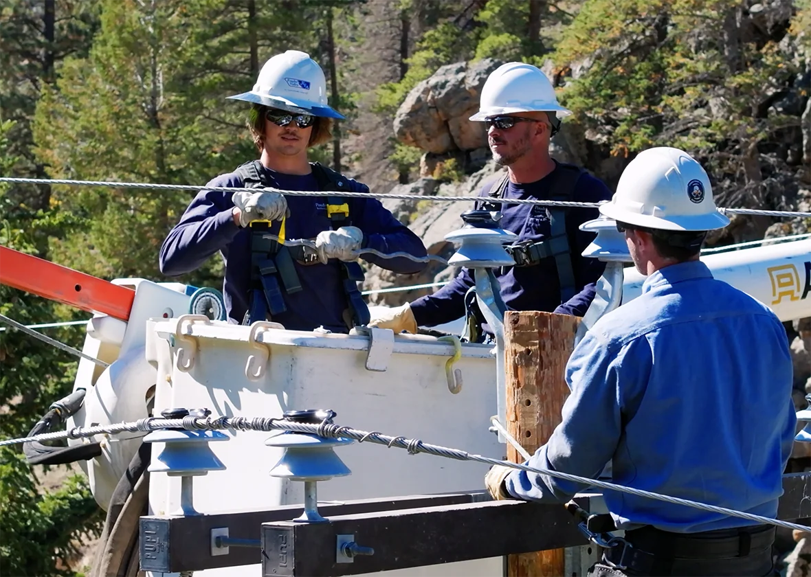 PVREA crews in a utility truck bucket fixing electrical power equipment.