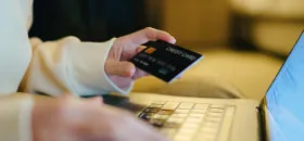 Hand holding credit card while on computer