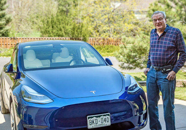 man smiling next to tesla electric car