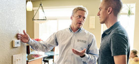 Energy consultant discussing thermostat with homeowner