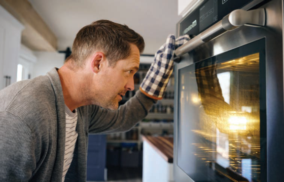 Man looking into oven at cooking food