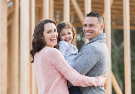 smiling family in front of home construction