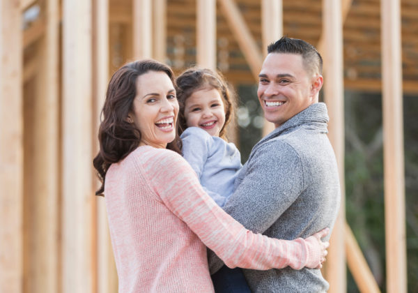 smiling family in front of home construction