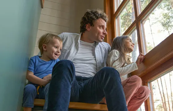 Dad and his two children sitting on steps in their house.